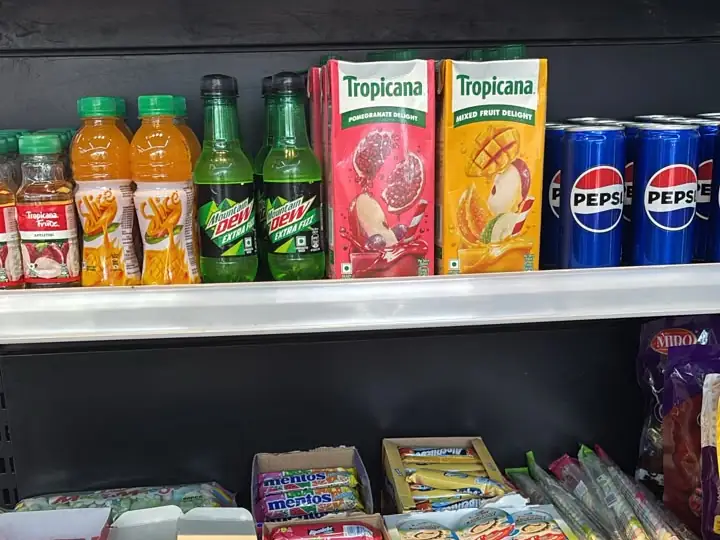 A shelf of Tropicana juices, Pepsi cans and soft drinks