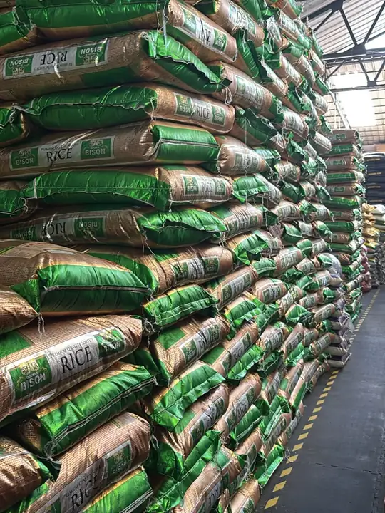 A warehouse aisle walled in with green-and-gold sacks of Bison rice